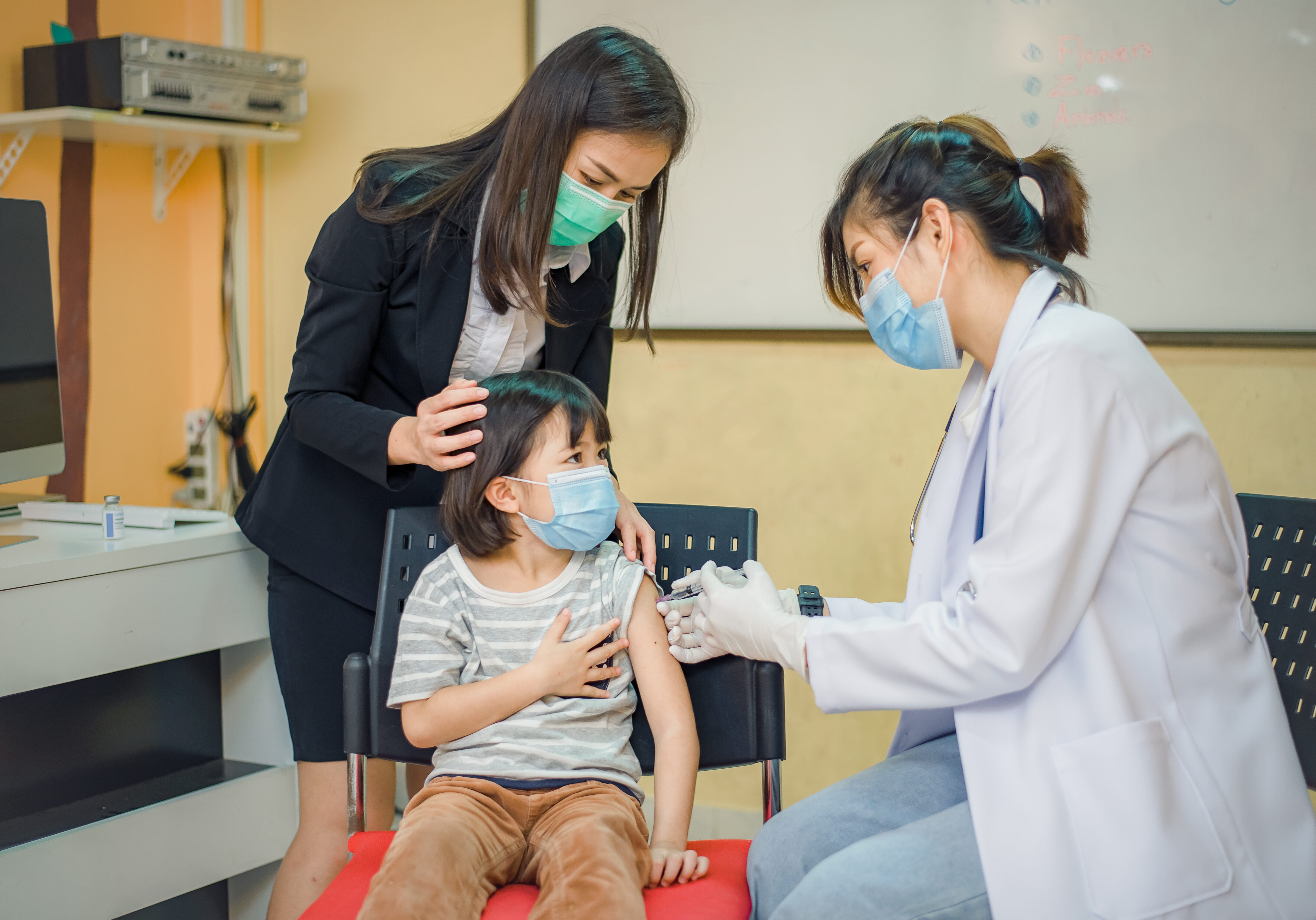 Coronavirus vaccination. Covid-19 vaccine. Doctor giving vaccinations to schoolchildren at School to prevent a serious epidemic among schoolchildren. Little boy getting flu shot. Virus prevention.