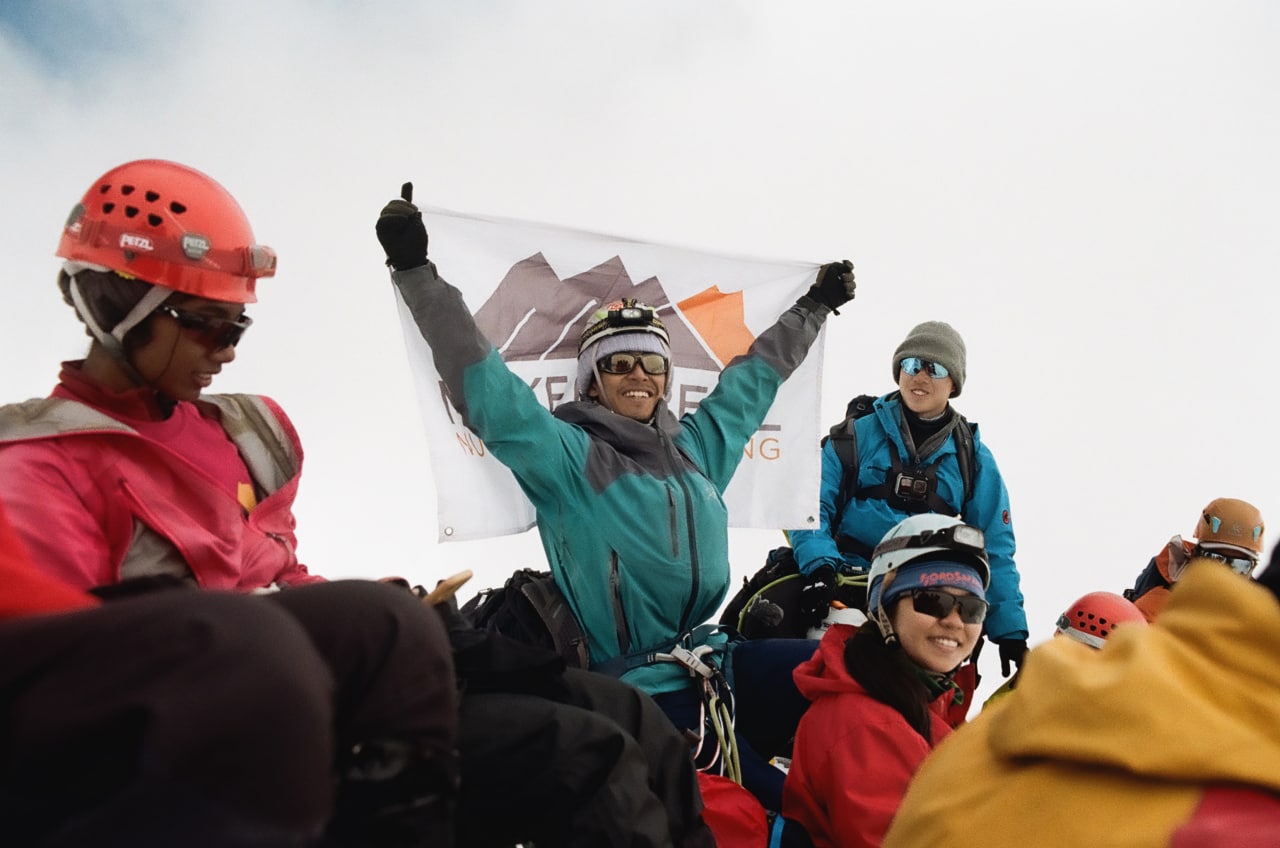 Danial Haqim raising a flag at the summit of Baden-Powell Peak in Nepal