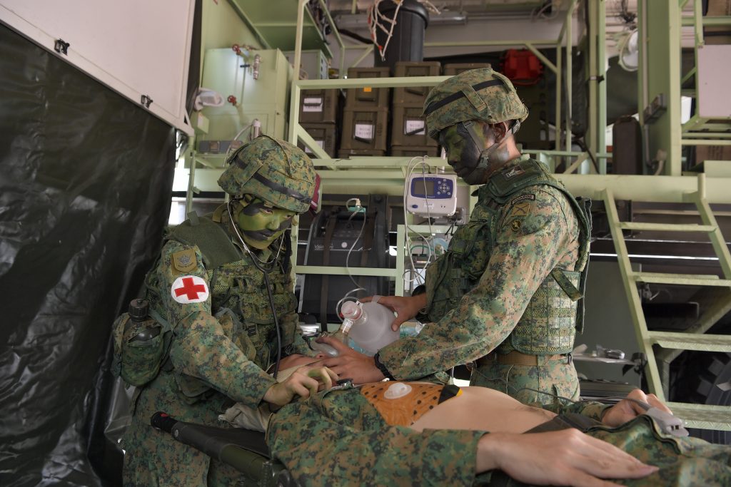 CPT (Dr) Ng (left) working with Staff Sergeant Muhammad Amir Bin Amat to treat a simulated casualty inside a BCS.