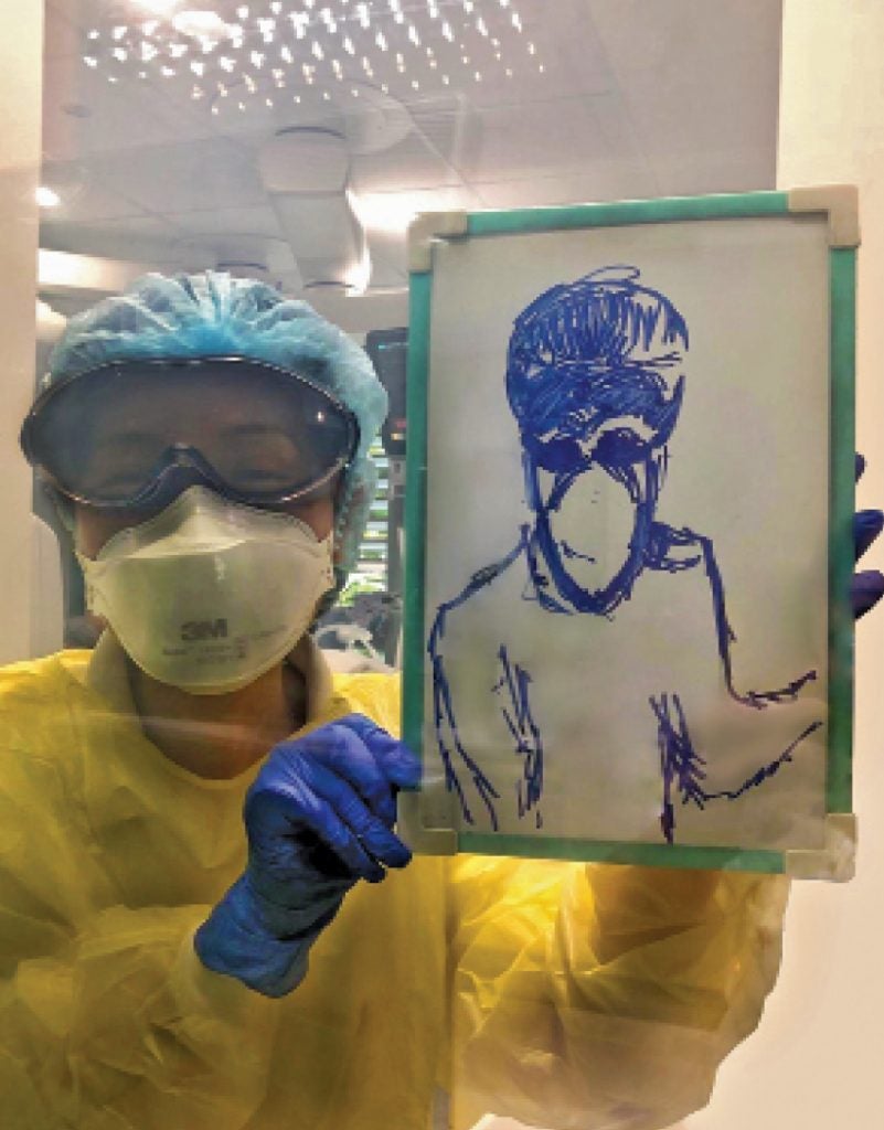 Assoc Prof Liaw in PPE, holding a portraiture of her drawn by a patient.