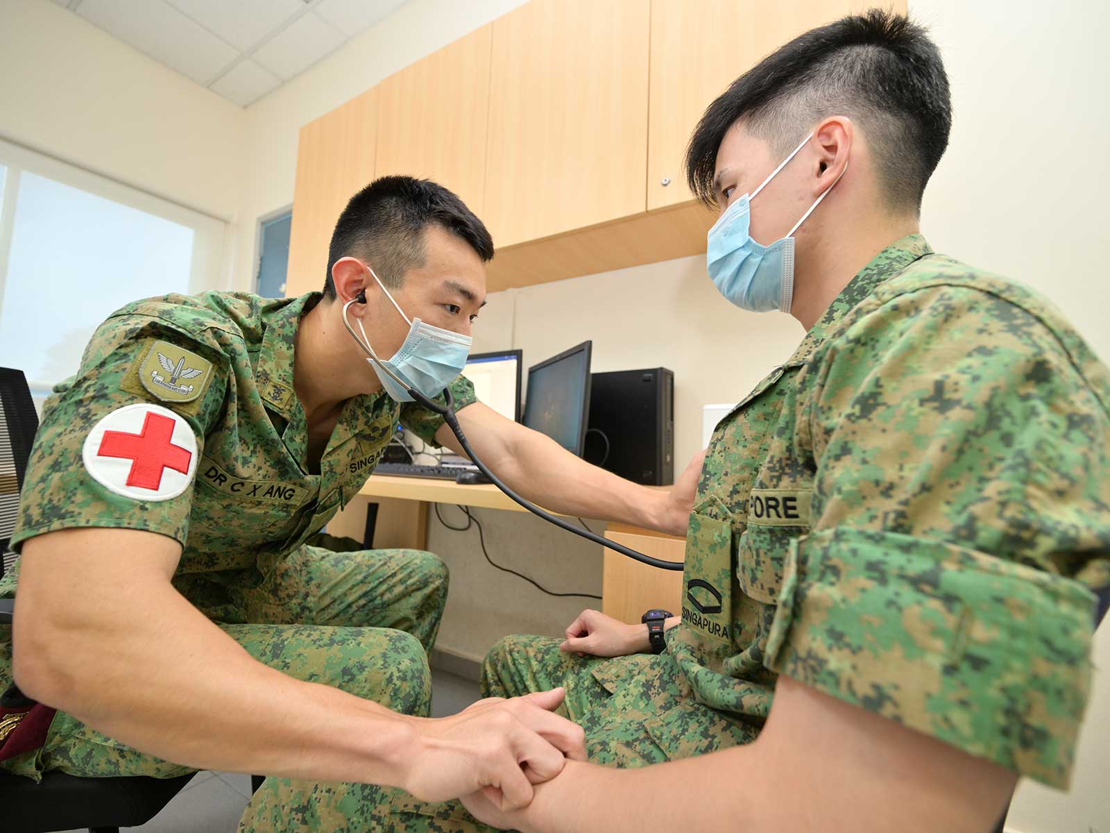 CPT (Dr) Ang (left) attending to a serviceman at the medical centre in Pasir Ris camp.