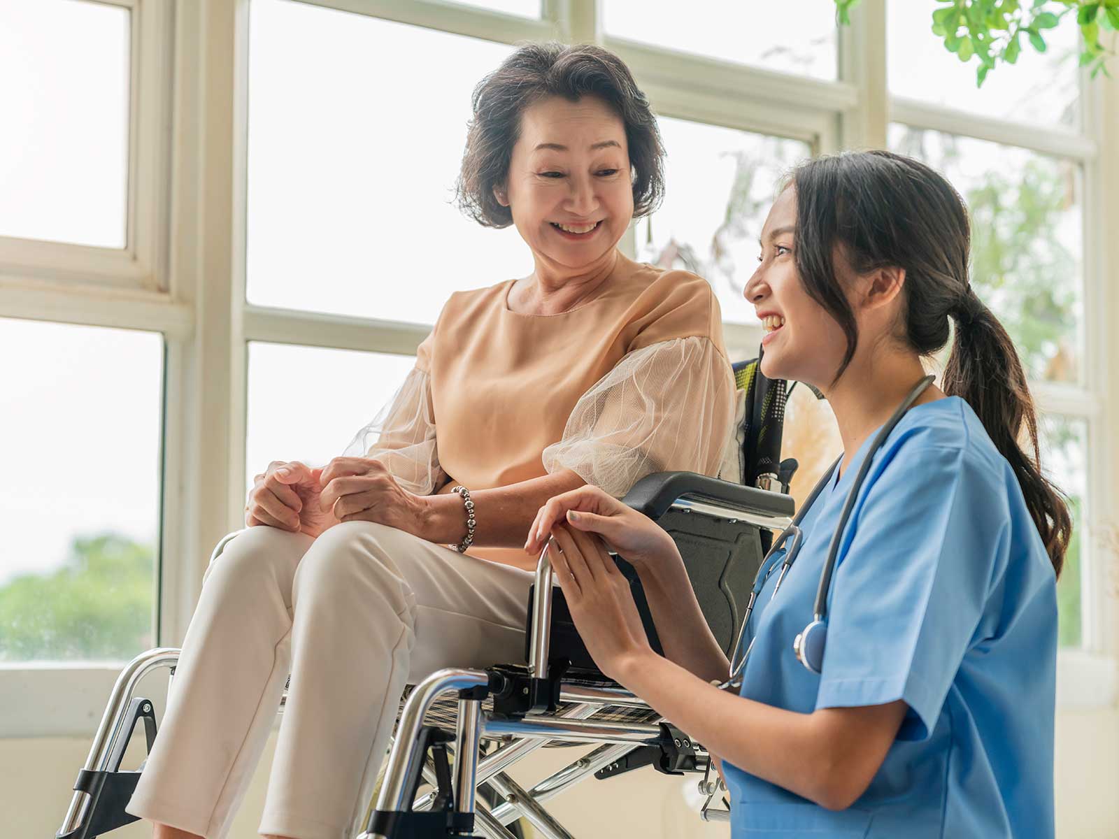 Photo of Asian elderly woman accompanied by a caring Asian nurse