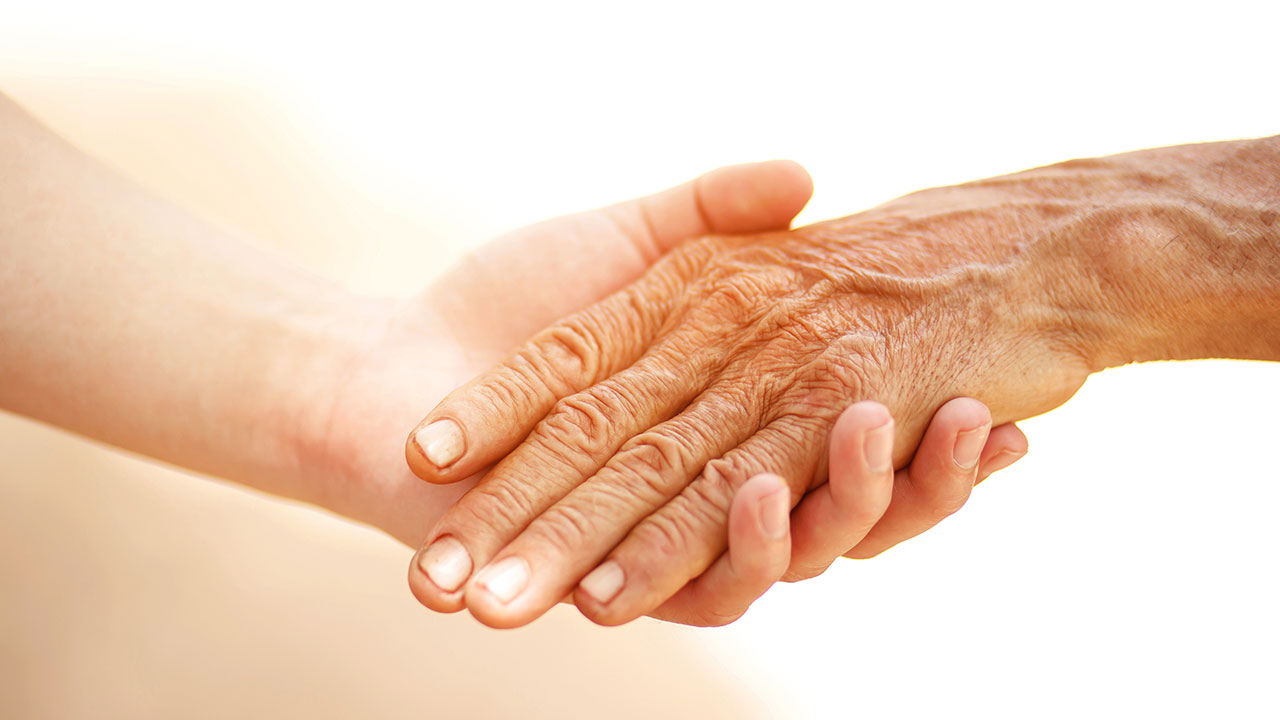 Image of young hands holding an old person's hand.