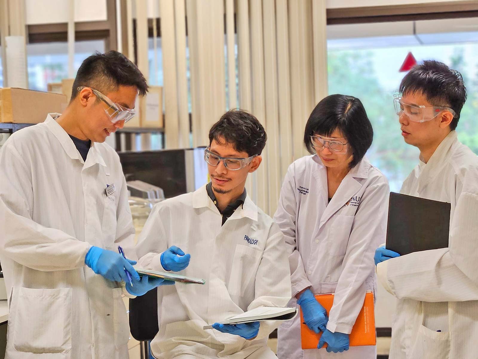 Research team members from Asst Prof Leong Sai Mun’s lab, discussing experimental data for their study on cancer cell altruism.