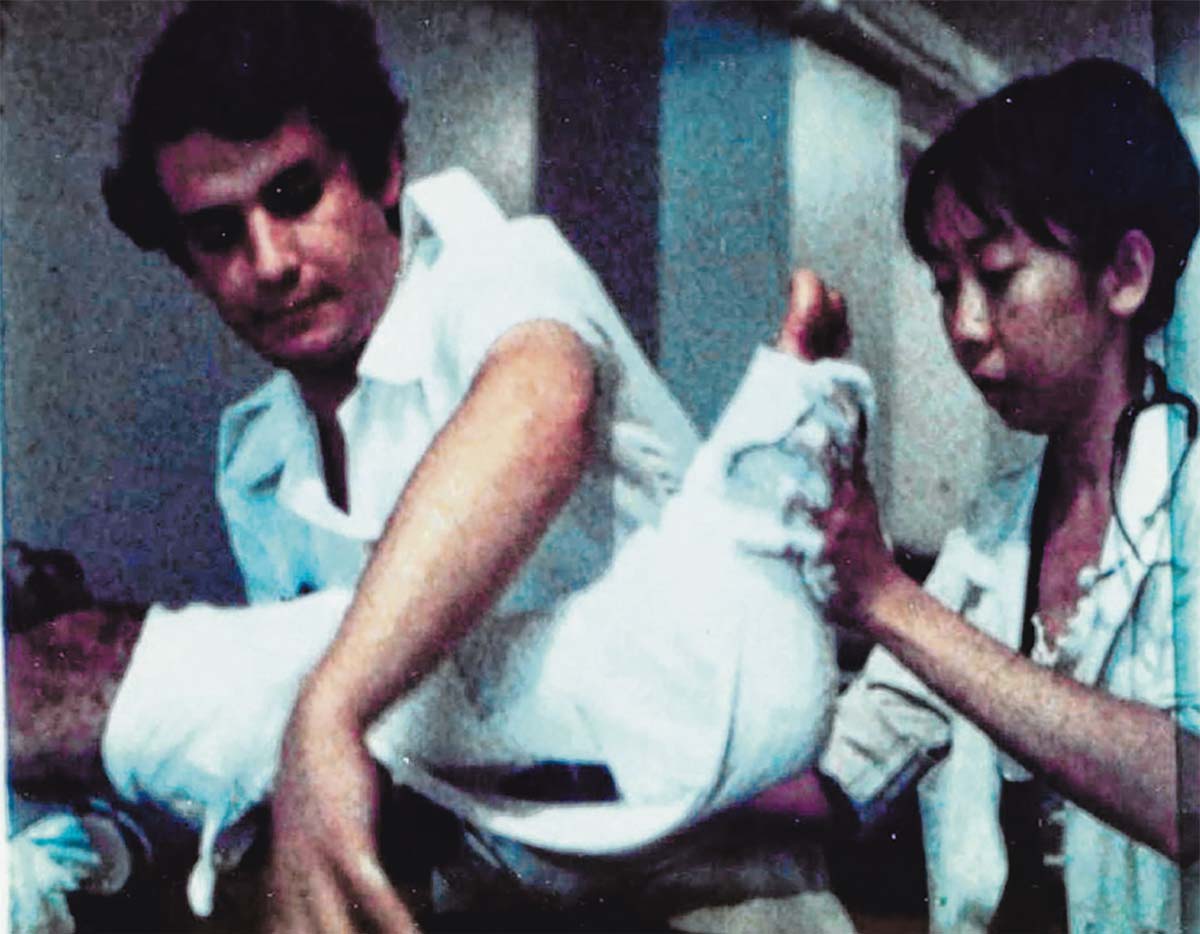 A colour-washed 1980s photo depicting a male nurse and a female doctor treating a patient at Gaza Hospital.