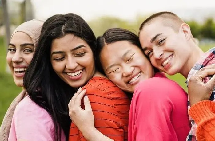 Multi-racial group of female youths embracing in an outdoor setting to represent the Global Centre for Asian Womens Health