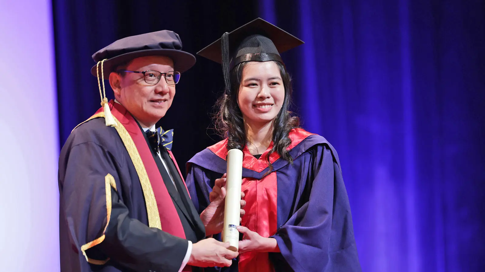 Dean of NUS Medicine, Professor Chong Yap Seng presenting a graduating medical student with her MBBS scroll.