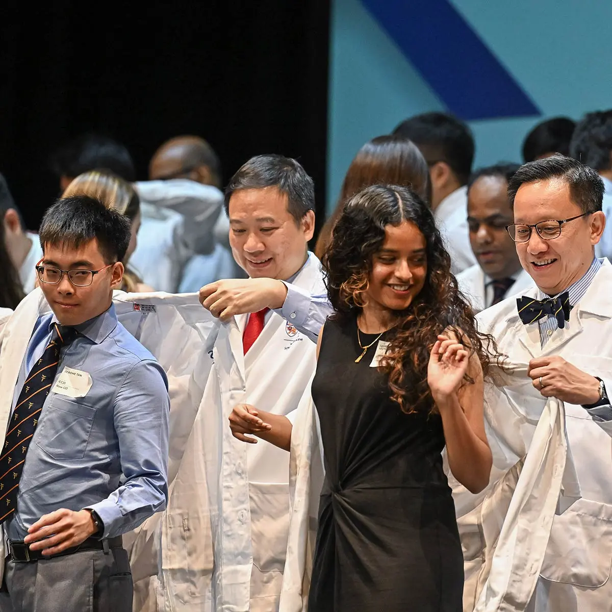 Guest-of-Honour, Dr Jeremy Lin and Dean of NUS Medicine, Professor Chong Yap Seng helping medical students don their first white coats.