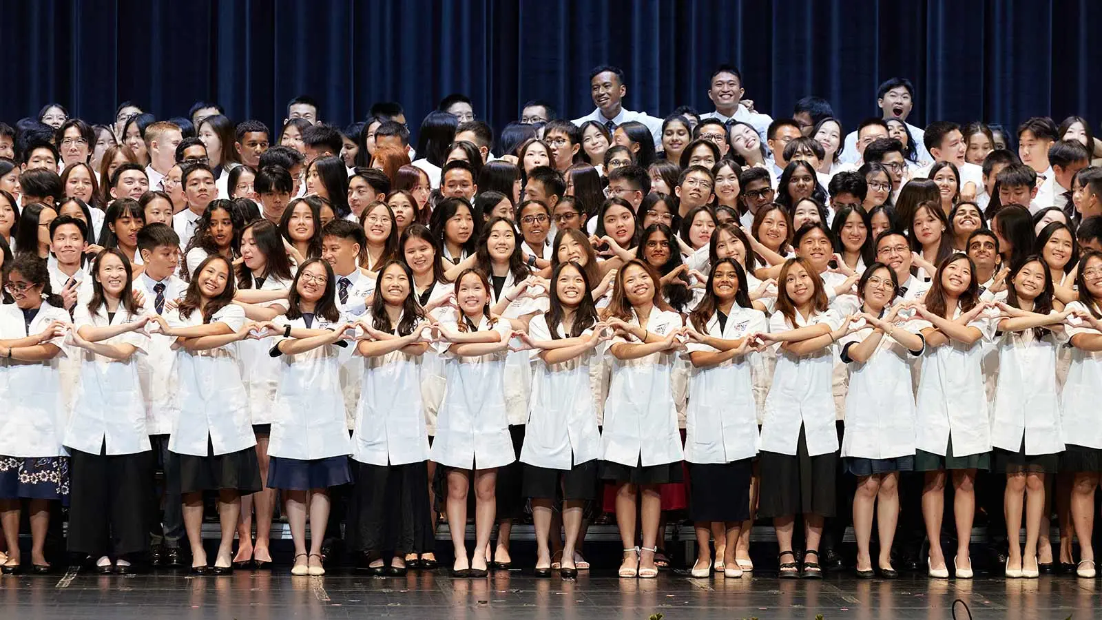 Fun shot of NUS Medicine Class of 2029 forming an interlinking chain of hearts.