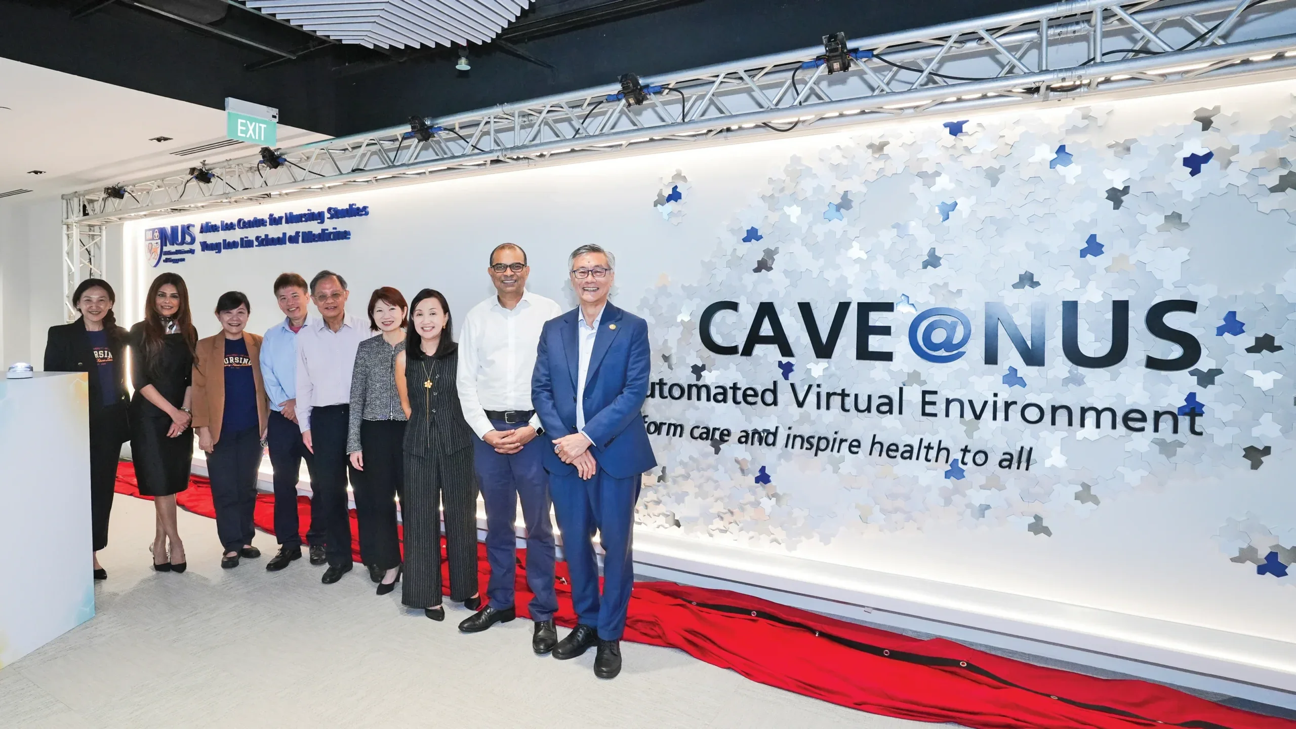 9 individuals standing to the left, with the right side showing the words CAVE @ NUS, and a long red cloth on the floor below the title tile.